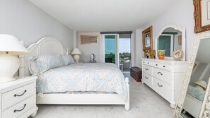 A bedroom with a bed, bedside tables, a dresser, a mirror, and a balcony door. - Rent This Luxury 5 Star Apartment on The Anchorage, Siesta Key Apartment 1029 (Siesta Key)