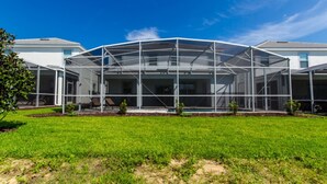 Ein modernes Haus mit einer großzügigen, überdachten Terrasse, umgeben von einer gepflegten Rasenfläche.
