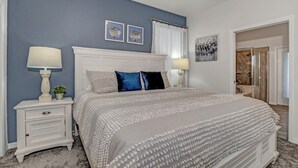 A bedroom with a large bed, white nightstands, and a blue accent wall. - Enjoy a Holiday of a Lifetime in a Luxury Villa on Windsor at Westside Resort, Orlando Villa 5051 (Kissimmee)