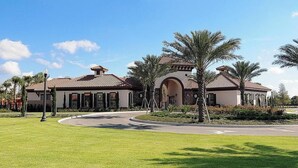 A large, two-story building with a tiled roof and arched entryway, surrounded by well-maintained lawns and palm trees. - 5 Star Villa Close to Disney, Orlando Villa 1558 (Davenport)