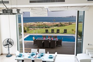 Uma área de refeições moderna com piscina e vista para o oceano.