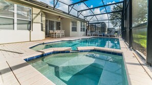 A swimming pool with a tiled edge, surrounded by a covered patio area with chairs and a table. - The Perfect Villa With a Beautiful Private Pool, Orlando Villa 4872 (Kissimmee)