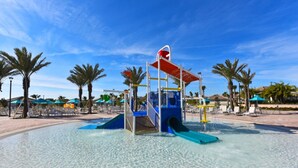 A water play area with slides and a climbing structure, surrounded by palm trees and lounge chairs. - The Ultimate Guide to Renting Your Luxury 8 Bedroom Mansion on Champions Gate Resort, Orlando Mansion 2526 (Davenport)