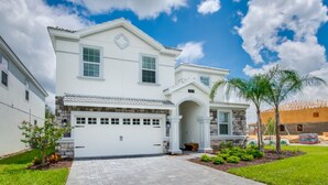 A two-story house with a white facade, a garage, and a paved driveway. - The Ultimate Guide to Renting Your Luxury 8 Bedroom Mansion on Champions Gate Resort, Orlando Mansion 2526 (Davenport)