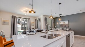 A modern kitchen with a central island, stainless steel appliances, and pendant lighting. - Rent a Luxury Townhome on Storey Lake Resort, Minutes From Disney, Orlando Townhome 3093 (Kissimmee)