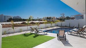A rooftop pool area with lounge chairs, a small pool, and a view of the cityscape. - Family Bliss Awaits: Protaras Villa 1572 (Paralimni)