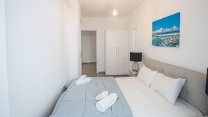 A hotel room with a bed, a nightstand, a lamp, and a painting of a beach scene. - Family Bliss Awaits: Protaras Villa 1572 (Paralimni)