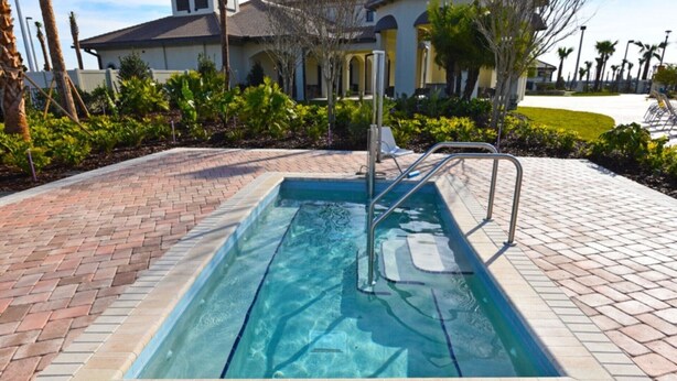A rectangular swimming pool with a metal ladder, surrounded by a brick border and a paved walkway. - Picture Renting Your Own Luxury Mansion on the Exclusive Champions Gate Resort, Close to Disney, Orlando Mansion 2599 (Davenport)