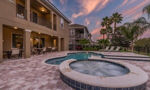 A two-story building with a pool and hot tub area, outdoor seating, and palm trees. - Rent This Luxury 5 Star Villa on Reunion Resort and Spa, Orlando Mansion 4619 (Kissimmee)
