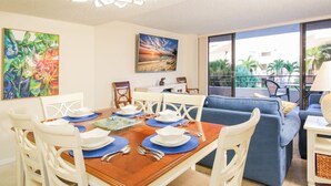 A dining area with a wooden table set for four, white chairs, and a blue sofa in the background.