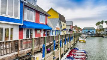 Una propiedad frente al agua con edificios de colores, un muelle de madera y barcos amarrados.