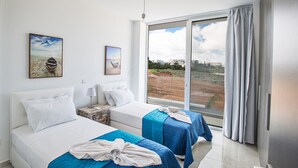 Ein Hotelzimmer mit zwei Betten, einem großen Fenster mit Landschaftsblick und einem Kunstwerk an der Wand.