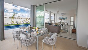Ein modernes Wohnzimmer mit Glastür, die auf einen Balkon mit Pool führt.