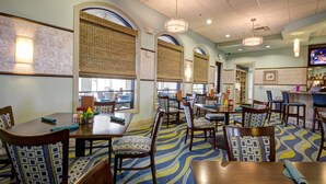 A hotel dining area with multiple tables and chairs, large windows with blinds, and a bar area with a television. - Luxury Contemporary Style Villa on Champions Gate Resort, Orlando Villa 4814 (Davenport)
