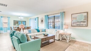 A living room with a sectional sofa, a coffee table, and a dining area with a table and chairs. - Luxury Contemporary Style Villa on Champions Gate Resort, Orlando Villa 4814 (Davenport)