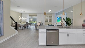 A modern kitchen with white cabinetry, a dishwasher, and a dining area with a table and chairs. - Picture Renting Your Own Luxury Mansion on the Exclusive Storey Lake Resort, Close to Disney, Orlando Mansion 5043 (Kissimmee)