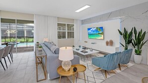 A modern living room with a sofa, chairs, a coffee table, and a TV on the wall. - Picture Renting Your Own Luxury Mansion on the Exclusive Storey Lake Resort, Close to Disney, Orlando Mansion 5043 (Kissimmee)