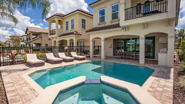A swimming pool with lounge chairs, a barbecue area, and a covered patio with outdoor furniture. - Luxury Private Villa With Large Pool on Reunion Resort and Spa, Orlando Villa 4588 (Kissimmee)