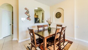 Un comedor con una mesa y sillas de madera, un jarrón con plantas secas y platos decorativos en la pared.