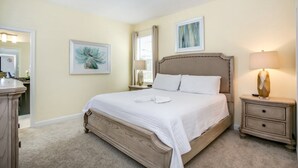 Un dormitorio con una cama grande, una mesita de noche, un aparador y dos obras de arte enmarcadas en la pared.
