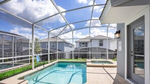 Un área de piscina cubierta con cerramiento de vidrio, un jacuzzi y vistas a edificios residenciales.