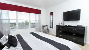 Een slaapkamer met een bed, een dressoir, een stoel en een televisie.
