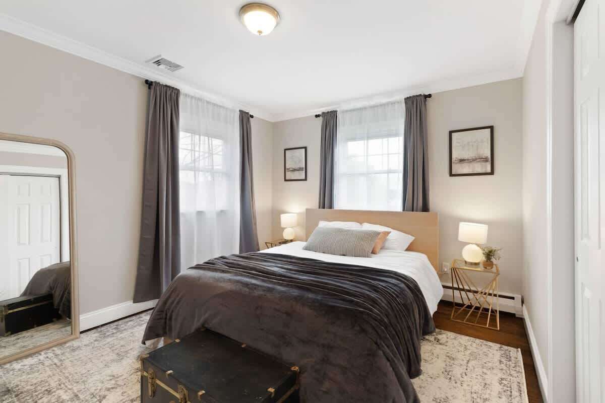Quarto de hotel com cama, abajures, espelho, mesinha com luminária e vista para o exterior.