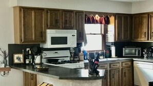 A kitchen with wooden cabinets, a white stove, a microwave, and a built-in island with a sink.