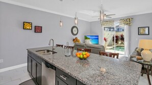 A modern kitchen with granite countertops, a built-in dishwasher, and a dining area with a sofa and chairs.