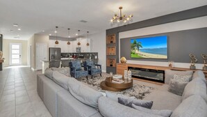 Een moderne woonkamer met een grote grijze modulaire bank, een open haard en een flatscreen televisie aan de muur.