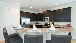 A modern kitchen with dark cabinets, stainless steel appliances, granite countertops, and a central island with bar seating.