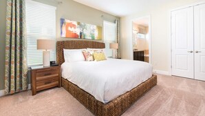 A bedroom with a large bed, a nightstand, a lamp, and a painting on the wall.
