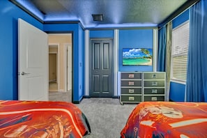 A bedroom with two beds, a dresser, a television, and a door leading to another room. - Your Beautiful Mansion on the Prestigious Storey Lake Resort, Orlando Mansion 3658 (Kissimmee)