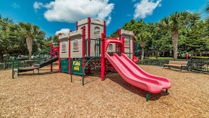 A playground with a red slide, climbing structures, and a castle-like playhouse. - Beautiful Villa With First Class Amenities on Windsor Hills Resort, Orlando Villa 4765 (Kissimmee)