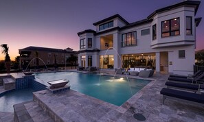 A modern two-story house with a swimming pool, outdoor seating, and a well-lit patio area. - Rent This Luxury 5 Star Villa on Reunion Resort and Spa, Orlando Mansion 4573 (Kissimmee)