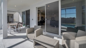 Une terrasse extérieure moderne, aménagée avec des meubles en osier, un coin repas et une vue sur une piscine.