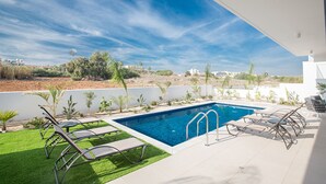 A modern outdoor swimming pool with lounge chairs and a view of the landscape. - Your Beautiful Holiday Villa in Protaras and Close to the Beach, Protaras Villa 1567 (Paralimni)