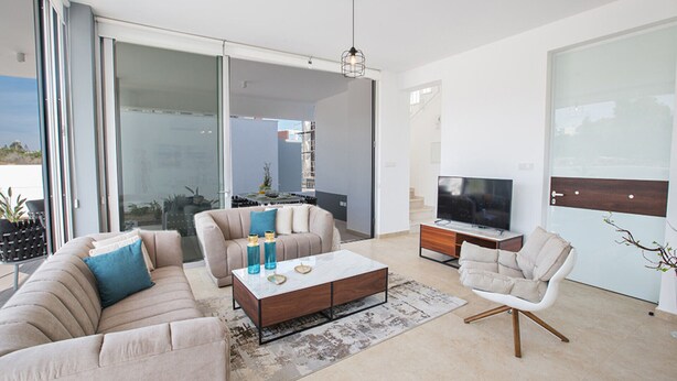 A modern living room with a sofa, coffee table, TV, and a sliding glass door leading to a balcony. - Your Beautiful Holiday Villa in Protaras and Close to the Beach, Protaras Villa 1567 (Paralimni)