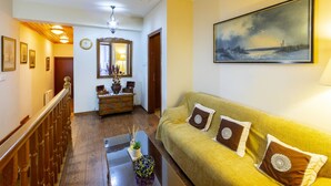 A living room with a wooden staircase, a sofa with patterned cushions, a painting on the wall, and a mirror above a wooden cabinet. - You and Your Family Will Love This Villa Close to the Beautiful Town of Limassol, Limassol Villa 1003 (Kato Amiantos)