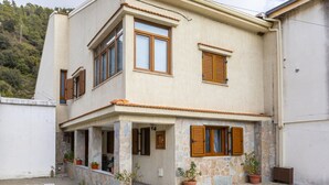 A two-story house with a stone facade, multiple windows with wooden shutters, and a small porch area with potted plants. - You and Your Family Will Love This Villa Close to the Beautiful Town of Limassol, Limassol Villa 1003 (Kato Amiantos)