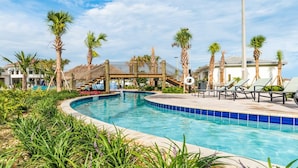 A swimming pool with a curved edge, surrounded by palm trees and lounge chairs. - The Ultimate 4 Bedroom Condo on Storey Lake Resort, Orlando Condo 4837 (Kissimmee)