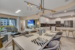 A modern kitchen with white cabinets, stainless steel appliances, and a dining area with striped table runners and grey upholstered chairs. - The Secret to Enjoying the Best Orlando Holiday While Staying on Storey Lake Resort, Orlando Condo 5041 (Kissimmee)