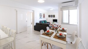 A modern living room with a sofa, TV, and artwork on the wall. - The Perfect Holiday Apartment Minutes From the Beach in Larnaca, Larnaca Apartment 1401 (Larnaca)