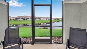 A view from a balcony with a large glass door, leading to a grassy area with a pond and a row of houses in the background. - You Have Found the Perfect Holiday Villa on Storey Lake Resort With Every 5 Star Amenity, Orlando Villa 3664 (Kissimmee)