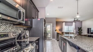A modern kitchen with a granite countertop, stainless steel appliances, and a central island with a sink. - You Have Found the Perfect Holiday Villa on Storey Lake Resort With Every 5 Star Amenity, Orlando Villa 3664 (Kissimmee)