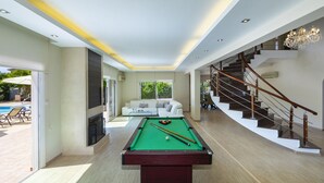 Una sala de estar moderna con una mesa de billar, una escalera y un sofá.