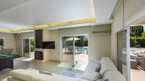 Un salón amplio con mesa de billar, un conjunto de sofás y una televisión.