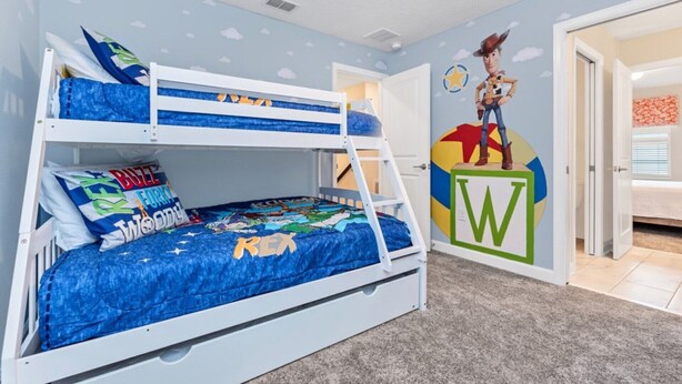 A bunk bed with a blue bedspread and pillows, a wall with a cartoon character, and a door with a colorful design. - Your Beautiful 5 Star Villa Minutes From Disney on the Prestigious Storey Lake Resort, Orlando Villa 3653 (Kissimmee)