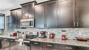 A modern kitchen with dark cabinets, stainless steel appliances, and a granite countertop. - You Will Love This 5 Star Villa Located on Storey Lake Resort, Orlando Villa 5492 (Kissimmee)