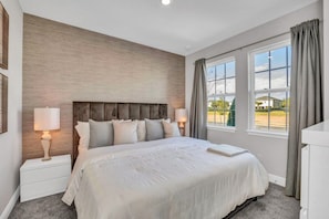A bedroom with a large bed, two bedside tables with lamps, a wooden headboard, and a view of a residential area through large windows. - You Have Found the Ultimate Luxury 10 Bedroom Mansion on Encore Resort, Orlando Mansion 5047 (Kissimmee)
